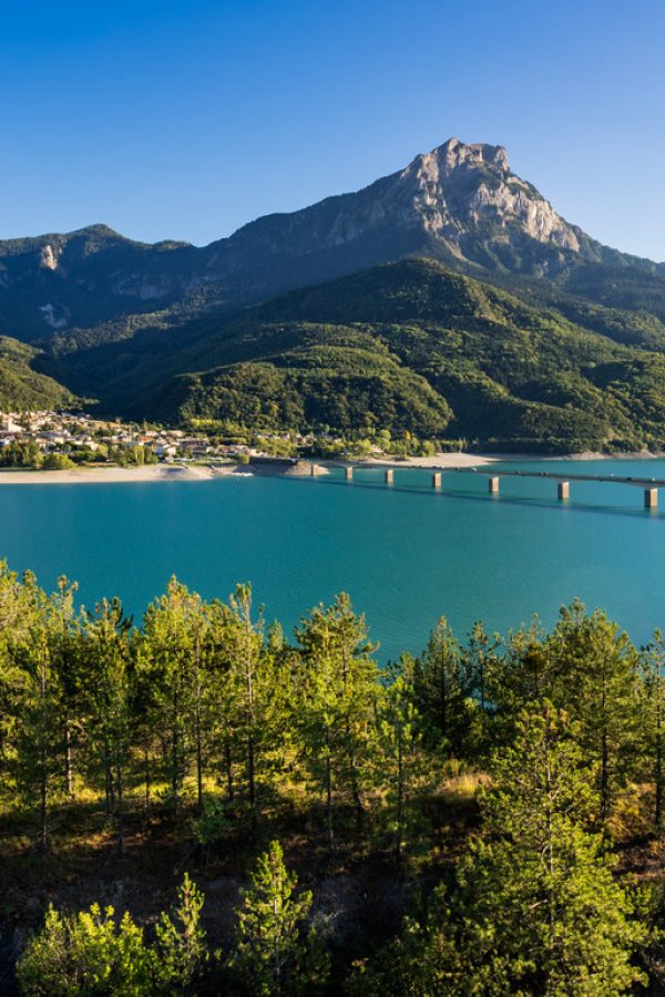 Summer panoramic view of Serre-Poncon Lake with Savines-le-Lac, its bridge and the Grand Morgon mountain peak. Hautes-Alpes, PACA Region, Southern French Alps, France
